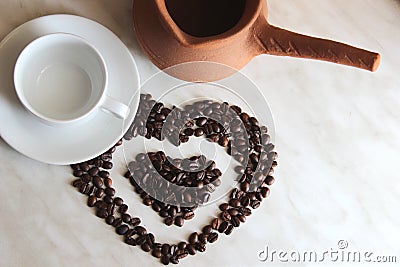 Brown clay Turk for cooking Arabic Turkish coffee, white clean Cup and saucer and roasted coffee beans in the shape of a Stock Photo