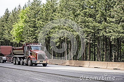 Brown compact powerful big rig tipper truck with two trailers running on the road to working place for the next load Stock Photo