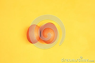 Brown eggs on yellow background. Size difference concept between two farm eggs Stock Photo