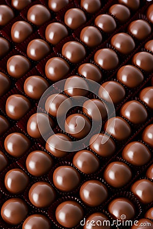 Brown filled chocolate, ball-shaped, in neat rows. Stock Photo