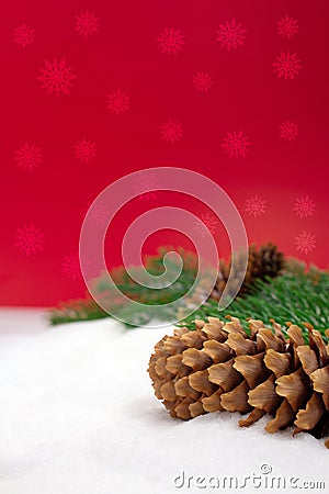 Brown fir cones on pine branches on snow. Behind red background with snowflakes. Vertical. Christmas, New Year Stock Photo