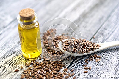Flaxseeds, jar with linseeds oil and spoon on gray table. Stock Photo