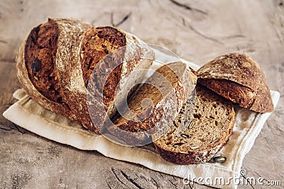 Brown fresh bread with seeds are cut into pieces on old wood background. Copy, empty space for text Stock Photo