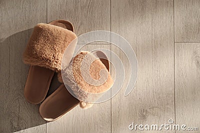 Brown fuzzy slippers on floor indoors, flat lay. Space for text Stock Photo