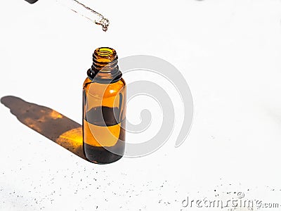 Brown glass with a dropper and a drop of essence. Bottle mockup cosmetic oil dropper on glass pipette. Copy space Stock Photo