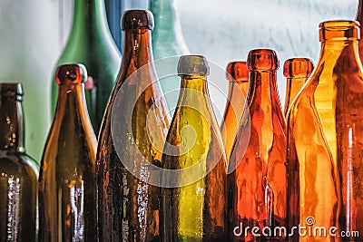 Brown and green old glass bottles on windowsill, with curtain. Closeup, daylight Stock Photo