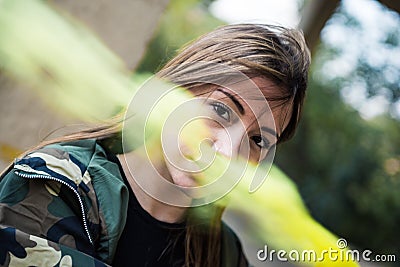 Brown hair girl holds a smoke bomb that throws yellow smoke around. Young girl wears an urban style, military jacket and piercing Stock Photo