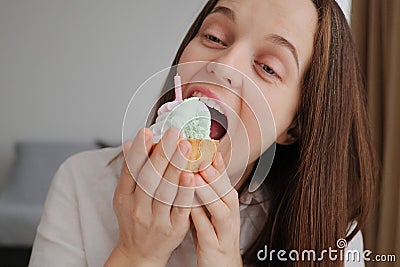 Brown haired beautiful woman biting appetizing piece of cake with cream has sweet tooth feeling temptation to eat delicious Stock Photo