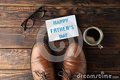 Brown leather shoes, inscription happy fathers day, cup of coffee and glasses on wooden background, space for text Stock Photo