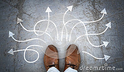 Brown leather shoes and many winding chalky arrows on asphalt Stock Photo