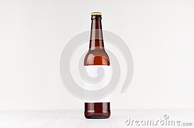 Brown longneck beer bottle 500ml with blank white label on white wooden board, mock up. Stock Photo