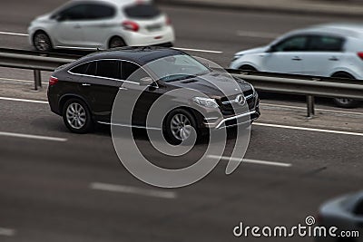 Brown mercedes rides on the road. Against a background of blurred trees Editorial Stock Photo