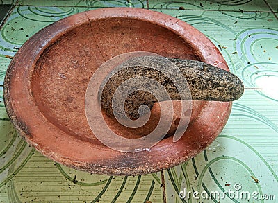 A brown mortar made of clay and a mortar made of natural stone on top of patterned green ceramic Stock Photo