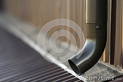 Brown new gutter metal system pipe. Vertical construction for draining rain water from building roof on the wall. Drain protection Stock Photo