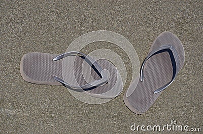 Brown pair of flip flop shoes on brown sand Stock Photo