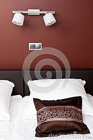 Brown pillow on bed with wall lighting Stock Photo