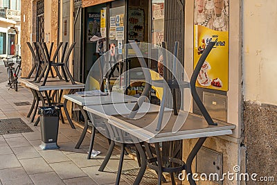 Brown plastic chairs stacked next to outdoor tables Editorial Stock Photo