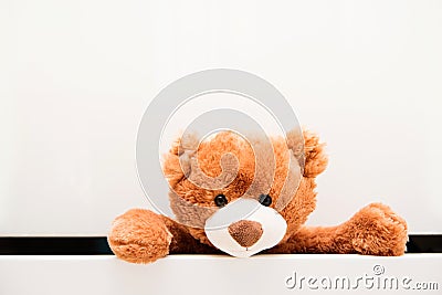 Brown plush toy Teddy bear crawling out of chest of white drawers Stock Photo