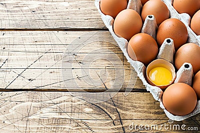 Brown raw eggs in factory packaging on rustic wooden background. Copy space Stock Photo