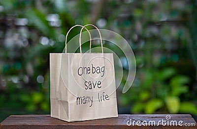 Brown recyclable paper shopping bag Placed on a wooden table, the backdroup is a green tree. Stock Photo