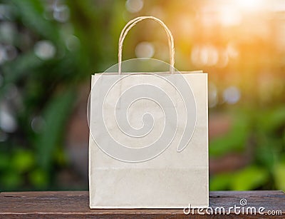 Brown recyclable paper shopping bag Placed on a wooden table, the backdroup is a green tree. Stock Photo