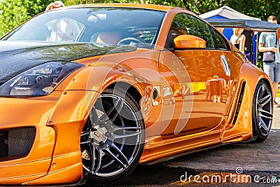 Brown restyled sports racing car moving on city street. Surface of bronze sport sedan car metal hood Editorial Stock Photo