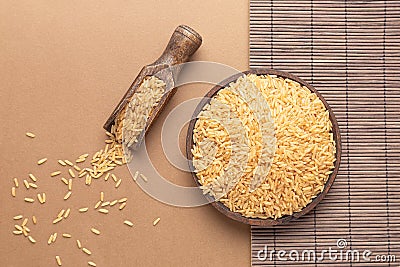 Brown rice on wooden plate and spoon, on brown and wood backround. Flat lay composition Stock Photo