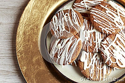 Brown Round Christmas Gingerbread cookies drizzled with White icing on a golden plate Stock Photo