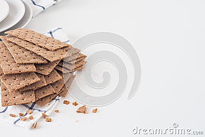 Brown rye crispy bread Swedish crackers on piece of cloth with plates on white background with space for text Stock Photo