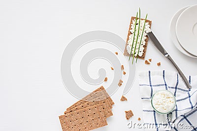 Brown rye crispy bread Swedish crackers with spread cottage cheese, decorated with thin green onion, on piece of cloth Stock Photo