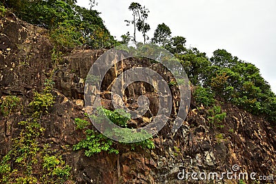 Brown Stone Cliff View with small tree on the side of road Stock Photo