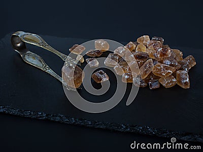 Brown sugar on black background cubes nippers Stock Photo
