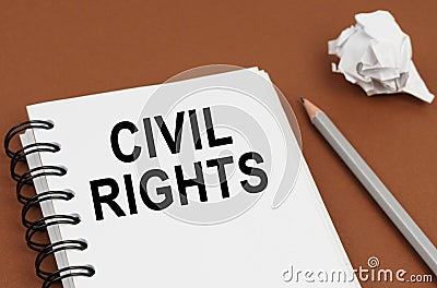 On a brown surface lies a pen, crumpled paper and a notepad with the inscription - CIVIL RIGHTS Stock Photo