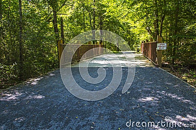 Brown wooden fence paved bridge walking trail distant view Stock Photo