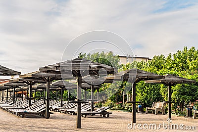 Brown wooden loungers and umbrellas. Rows resting places. Stock Photo