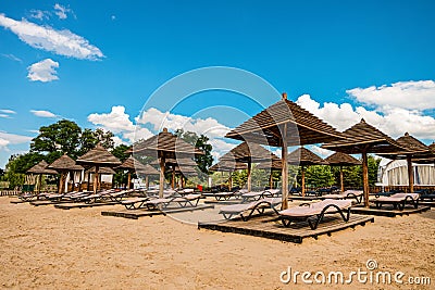 Brown wooden loungers and umbrellas on empty sandy beach Stock Photo