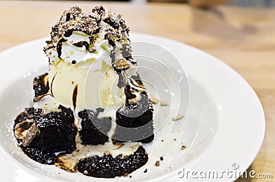 brownie dessert on a white plate with chocolate syrup and vanilla ice cream.pecans on the top. Stock Photo