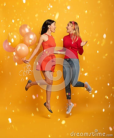 Girls ready for a party with balloons. Joyful an happiness expression. Yellow background Stock Photo