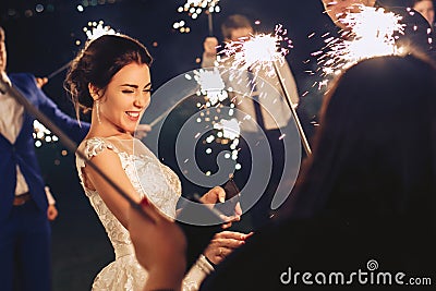 The bride and the guests hold the sparklers and amuse themselves Stock Photo