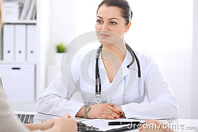 Brunette female doctor talking to patient at hospital office. Physician says about medical exams results for choosing Stock Photo
