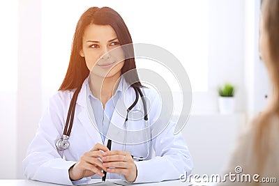 Brunette female doctor talking to patient at hospital office. Physician says about medical exams results for choosing Stock Photo
