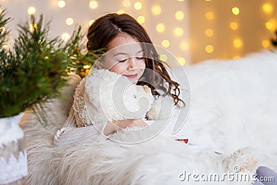 A brunette gilr in front of fur-tree and fireplace with candles and gifts. A girl dreaming. New year`s eve. Christmas . Stock Photo