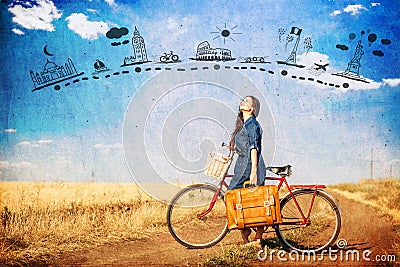 Brunette girl with bycicle and suitcase on country side road. Stock Photo