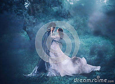 Brunette girl ghost and spirit of nightly mysterious cold blue forest, lady in white vintage lace dress with long flying Stock Photo