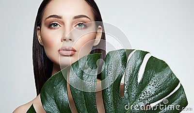 Brunette girl in palm leaves. Beautiful young woman with Make-up Stock Photo