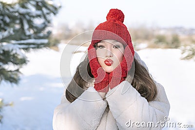 Brunette girl in red knitted hat and mittens in winter outdoors. Little red riding hood Stock Photo