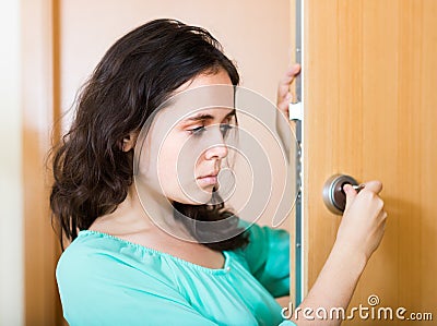 Brunette looking at broken lock of door Stock Photo