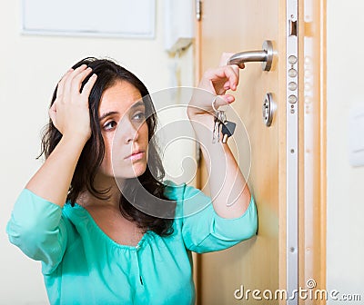 Brunette looking at broken lock of door Stock Photo