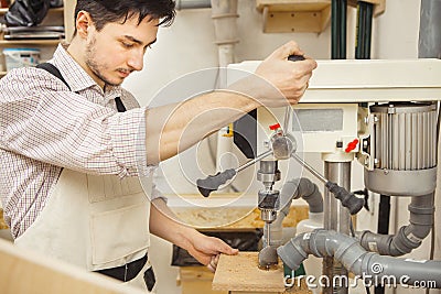 Brunette man bored wooden board on drilling machine Stock Photo