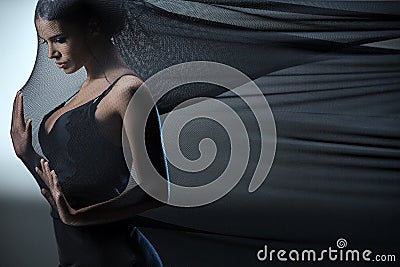 Brunette stretches stretch mesh fabric in front of Stock Photo